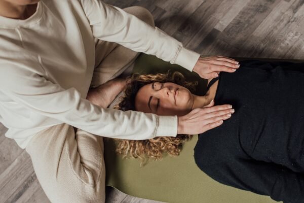 Woman laying down and receiving reiki and scalar therapy from another woman