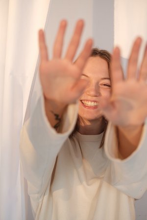 Young woman holding hands out in front as if sending Reiki