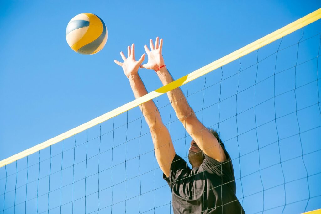 Man hitting volley ball over net