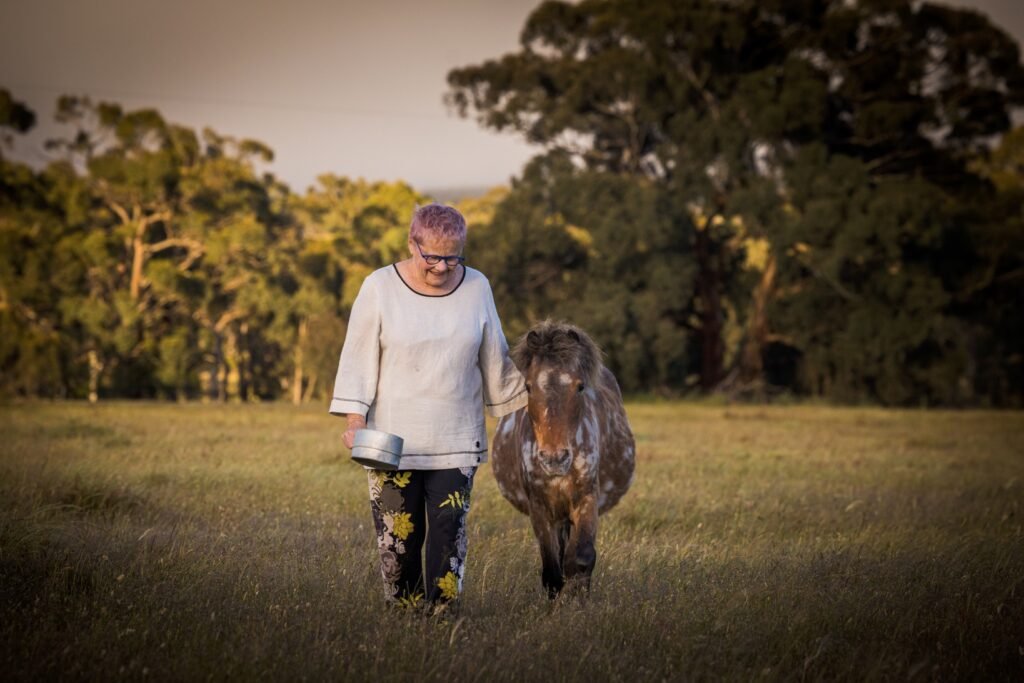 Noelene walking the paddock with her Pinto pony Paris who has helped teach her about energy healing for people and pets