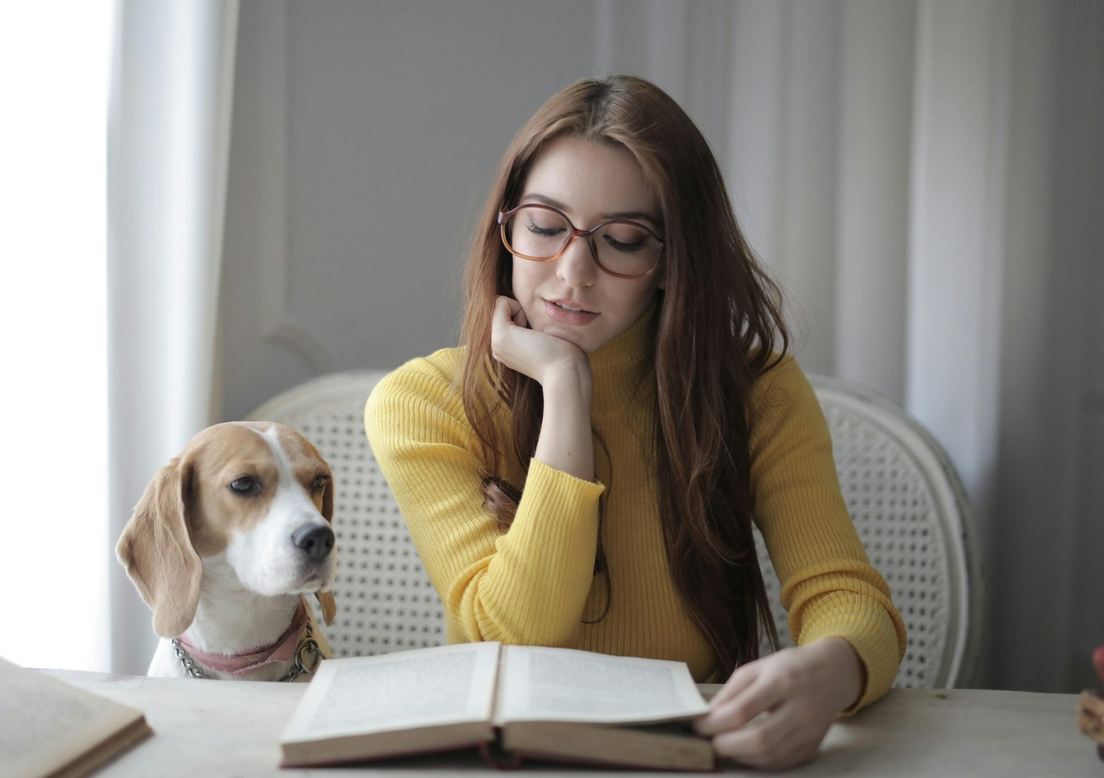 woman reading book with dog beside her